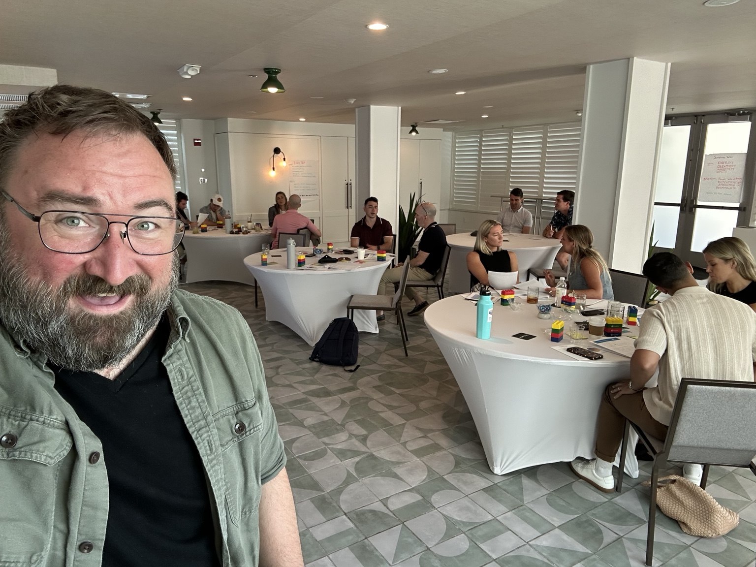 Justin Reinert in a workshop room while participants talk around tables